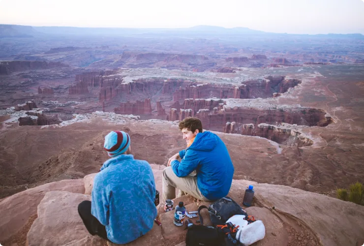 Two hikers enjoying sunset at Grand Canyon.